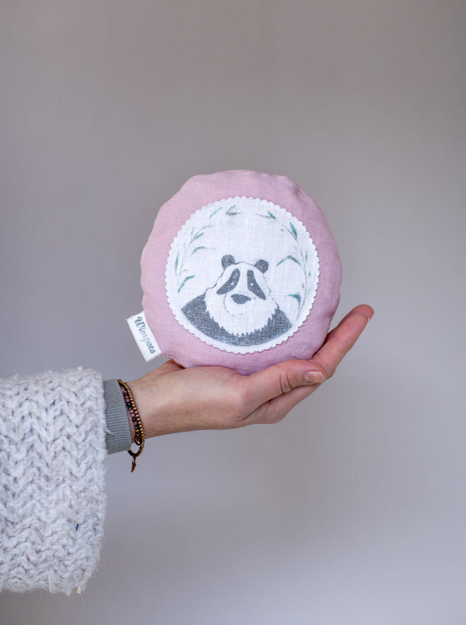 Rundes Dinkelkissen aus Leinen Farbe Altrosa mit Panda auf weißem Patch.